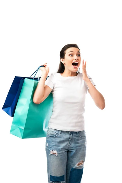 Donna sorpresa che tiene borse della spesa isolate sul bianco — Foto stock