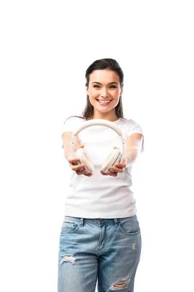 Selective focus of young woman in white t-shirt holding wireless headphones isolated on white — Stock Photo