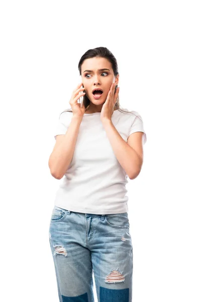 Shocked young woman in white t-shirt talking on smartphone isolated on white — Stock Photo