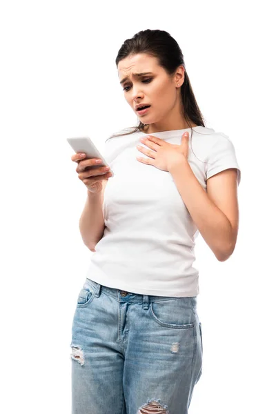Стурбована молода жінка дивиться на смартфон ізольовано на білому — стокове фото