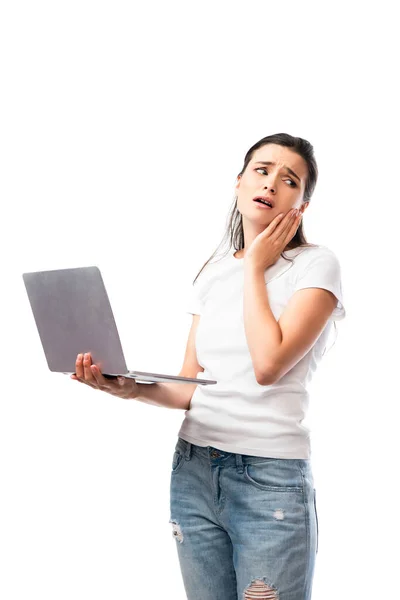 Mulher morena preocupado em branco t-shirt segurando laptop isolado no branco — Fotografia de Stock