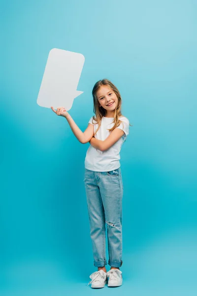 Vista completa de la muchacha en jeans y camiseta blanca sosteniendo la burbuja del discurso en azul - foto de stock
