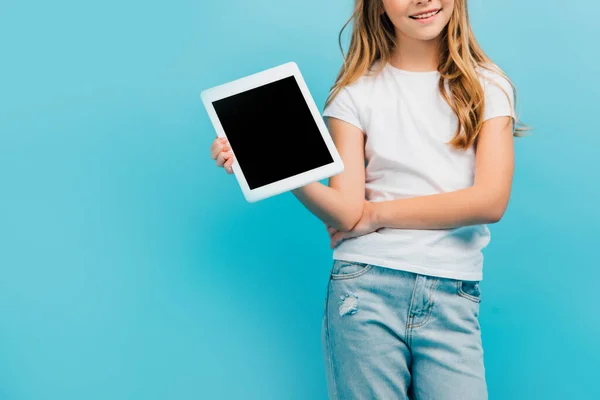 Cropped view of girl in white t-shirt and jeans showing digital tablet with blank screen isolated on blue — Stock Photo