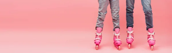 Обрезанный вид матери и ребенка в джинсах и роликовых коньках на розовом, горизонтальном изображении — стоковое фото