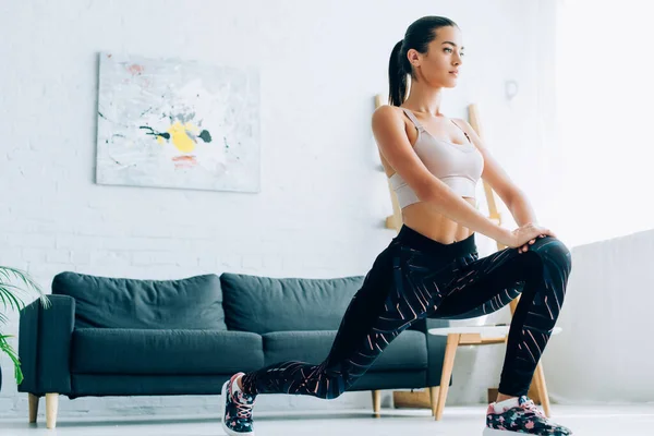 Sportswoman ajuste fazendo lunges durante o treinamento em casa — Fotografia de Stock