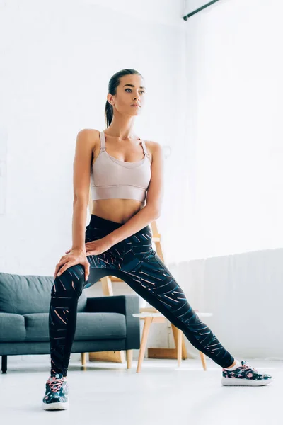 Selective focus of focused sportswoman looking away while training in living room — Stock Photo