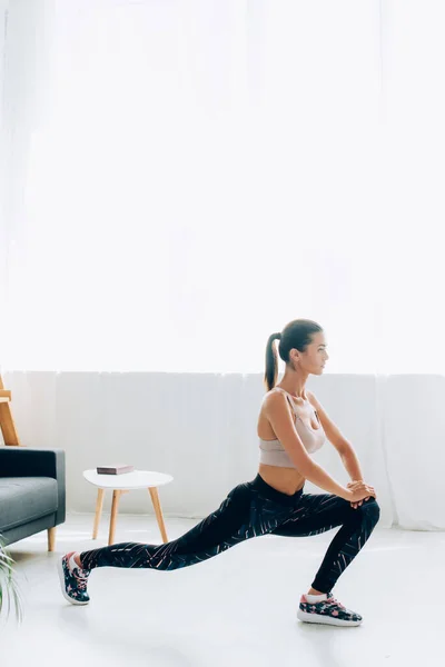 Selective focus of brunette woman doing lunges at home — Stock Photo