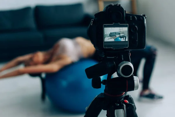 Selektive Fokussierung der Digitalkamera auf Stativ und Sportlertraining mit Fitnessball zu Hause — Stockfoto