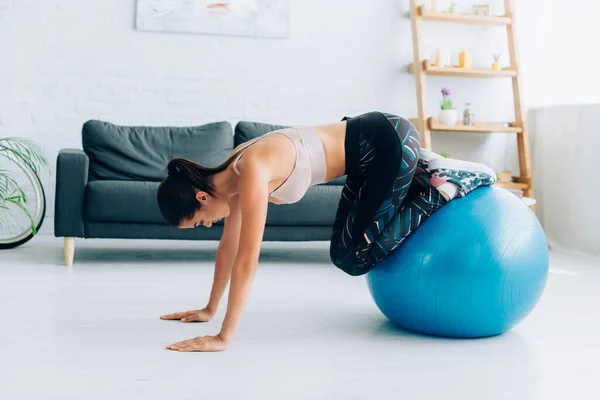 Side view of brunette sportswoman working out with fitness ball in living room — Stock Photo
