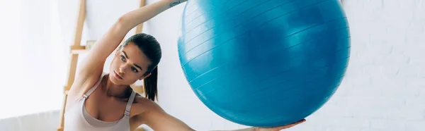 Горизонтальна концепція брюнетки спортсменки тримає фітнес м'яч вдома — стокове фото