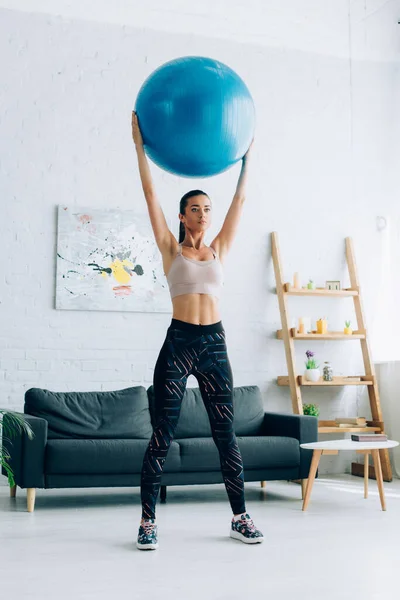 Young sportswoman holding fitness ball in living room — Stock Photo