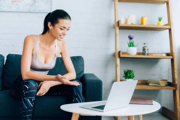 Selective focus of sportswoman pointing with hand at laptop in living room — Stock Photo