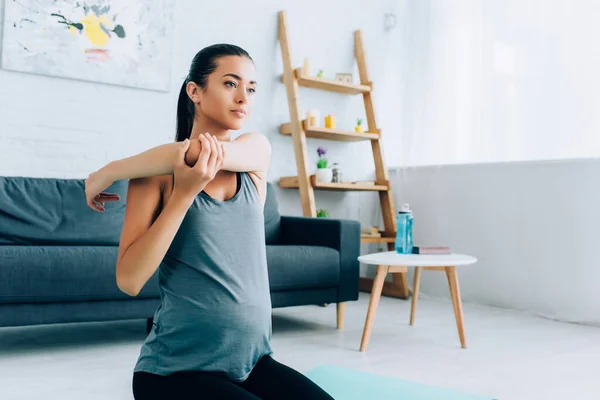 Young pregnant woman warming up in living room — Stock Photo