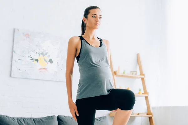 Mujer embarazada haciendo ejercicio en la sala de estar - foto de stock