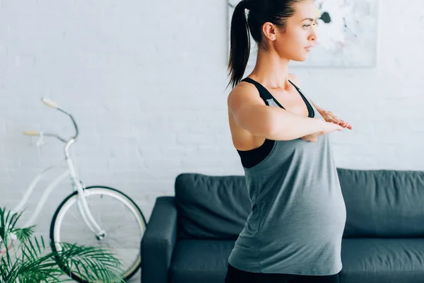 Young pregnant sportswoman working out in living room — Stock Photo