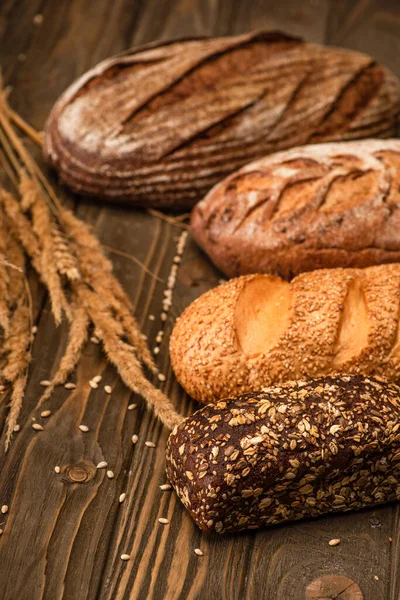 Selective focus of fresh baked bread loaves with spikelets on wooden surface — Stock Photo