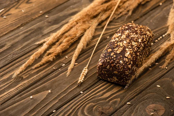 Messa a fuoco selettiva di pane appena sfornato con spikelets su superficie di legno — Foto stock