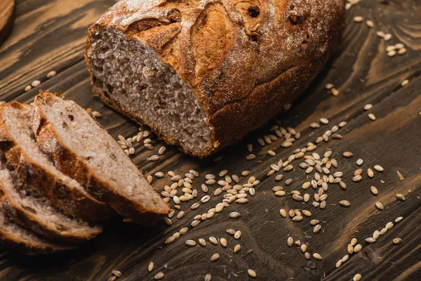 Pain frais coupé au four avec des graines sur la surface en bois — Photo de stock