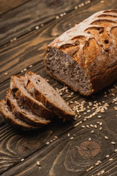 Cortar pão fresco assado com sementes na superfície de madeira — Fotografia de Stock