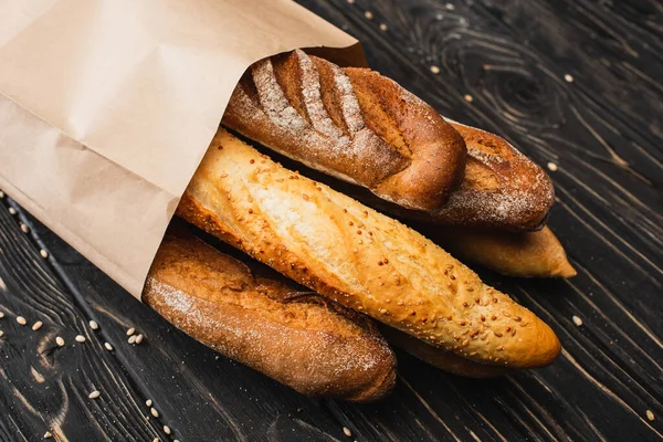 Panes de baguette recién horneados en bolsa de papel sobre superficie de madera - foto de stock