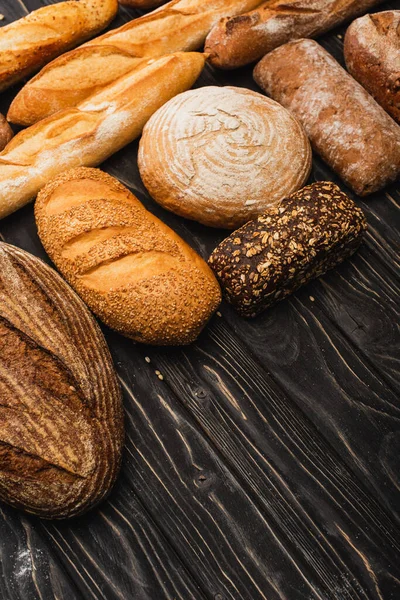 Fresh baked bread loaves on wooden black surface — Stock Photo