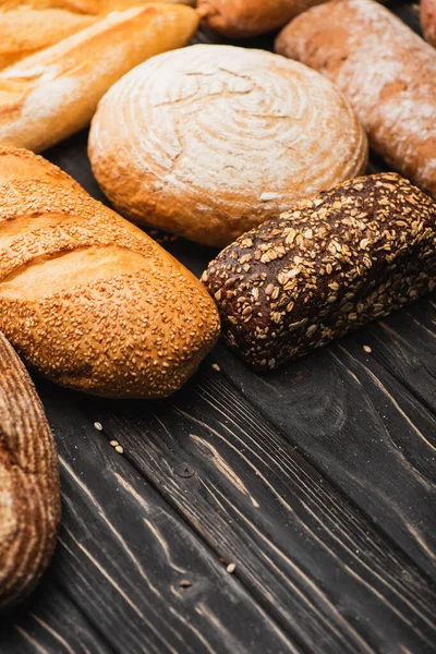 Fresh baked bread loaves on wooden black surface — Stock Photo