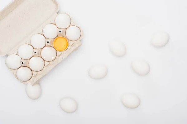 Top view of fresh chicken eggs and yolk in cardboard box isolated on white — Stock Photo