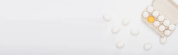Вид зверху на свіжі курячі яйця і жовток в картонній коробці ізольовані на білому, панорамний постріл — стокове фото