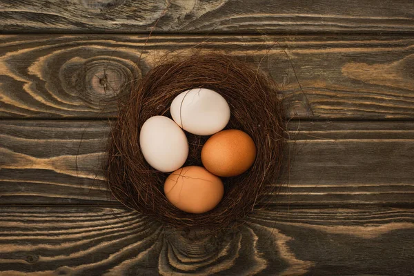 Вид зверху на свіжі курячі яйця в гнізді на дерев'яній поверхні — стокове фото