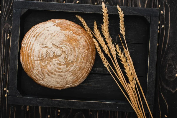 Вид сверху на свежий выпеченный белый хлеб с шипами на деревянной черной доске — стоковое фото