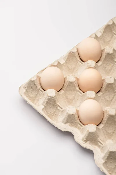 Close up view of fresh chicken eggs in cardboard egg tray on white background — Stock Photo