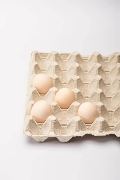 Fresh chicken eggs in cardboard egg tray on white background — Stock Photo