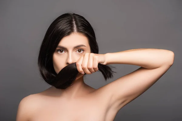 Naked brunette woman holding hair near face isolated on black — Stock Photo
