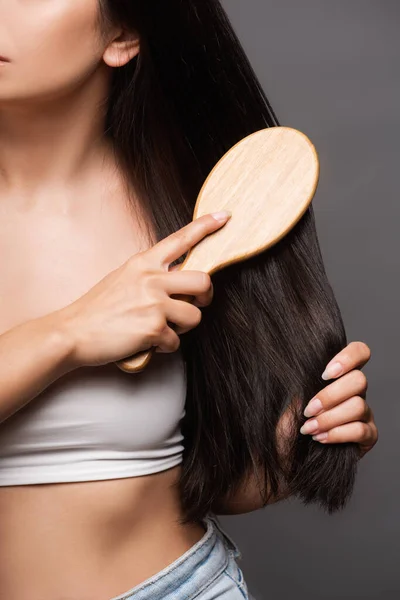 Cropped view of brunette woman brushing hair isolated on black — Stock Photo