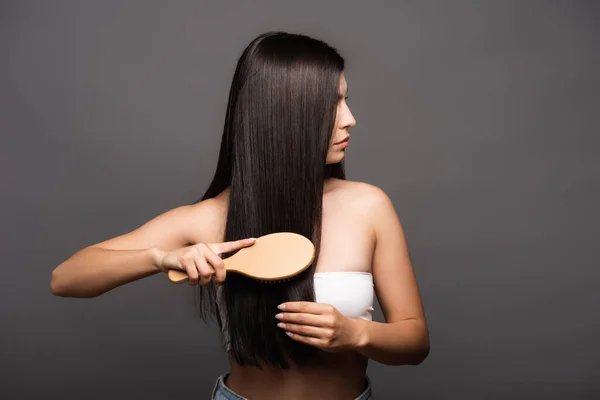 Abgeschnittene Ansicht der brünetten Frau Bürsten glänzendes Haar isoliert auf schwarz — Stockfoto