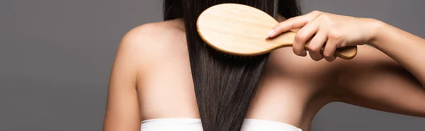 Partial view of brunette woman brushing shiny hair isolated on black, panoramic shot — Stock Photo