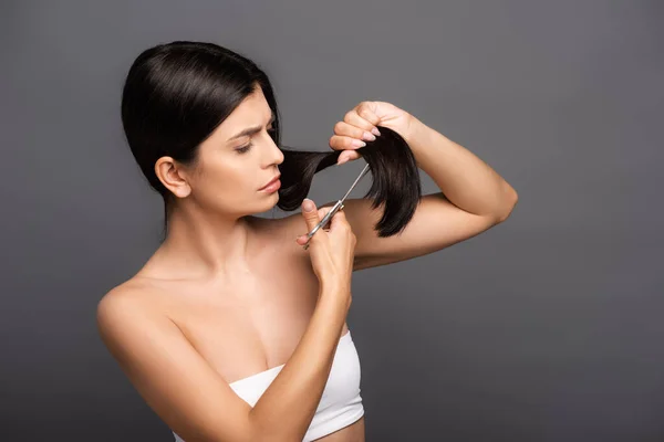 Brunette woman cutting hair isolated on black — Stock Photo