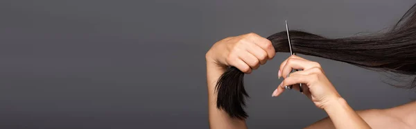Cropped view of naked brunette woman cutting hair isolated on black, panoramic shot — Stock Photo