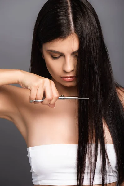 Брюнетка женщина стрижет волосы изолированы на черном — стоковое фото