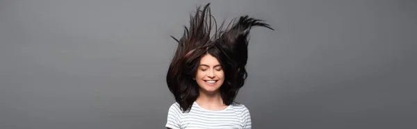 Morena de pelo largo mujer saltando y sonriendo aislado en negro, tiro panorámico - foto de stock