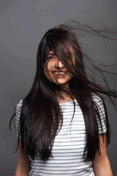 Viento soplando a través del pelo de la mujer morena aislado en negro - foto de stock