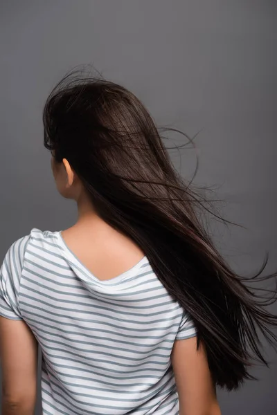 Vue arrière du vent soufflant à travers les cheveux de la femme brune isolée sur noir — Photo de stock