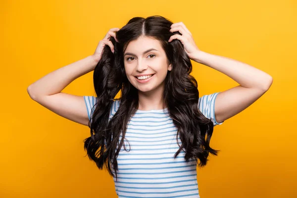 Brünette Frau mit lockigen langen Haaren und lächelt isoliert auf gelb — Stockfoto