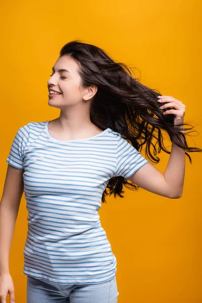 Wind blowing through brunette hair of woman with curls isolated on yellow — Stock Photo