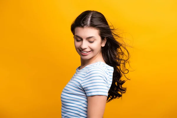 Wind blowing through brunette hair of woman with curls isolated on yellow — Stock Photo