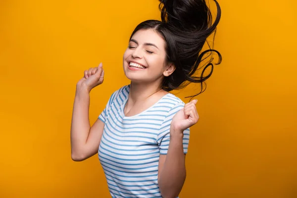 Brunette femme aux cheveux longs avec des boucles sautant isolé sur jaune — Photo de stock