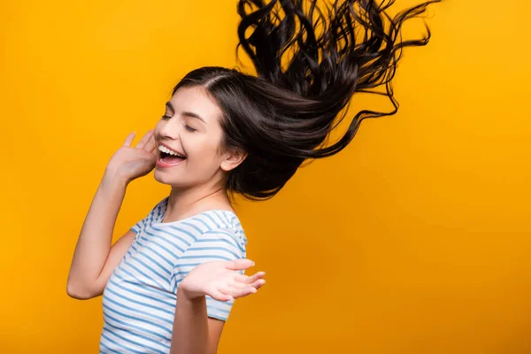 Morena mujer de pelo largo con rizos saltando aislado en amarillo - foto de stock