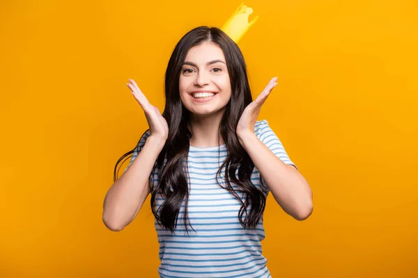 Brünette Frau in Papierkrone lächelt isoliert auf gelb — Stockfoto