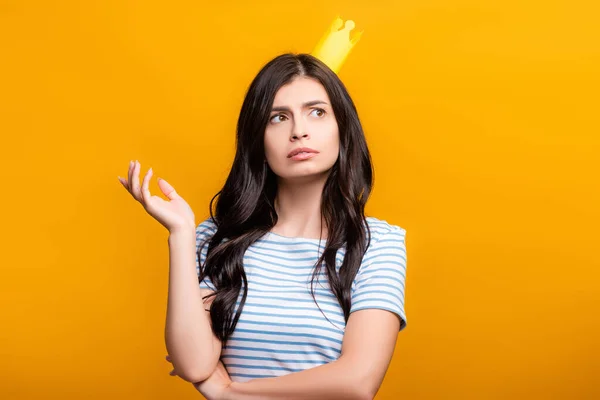 Pensive brunette woman in paper crown looking away isolated on yellow — Stock Photo