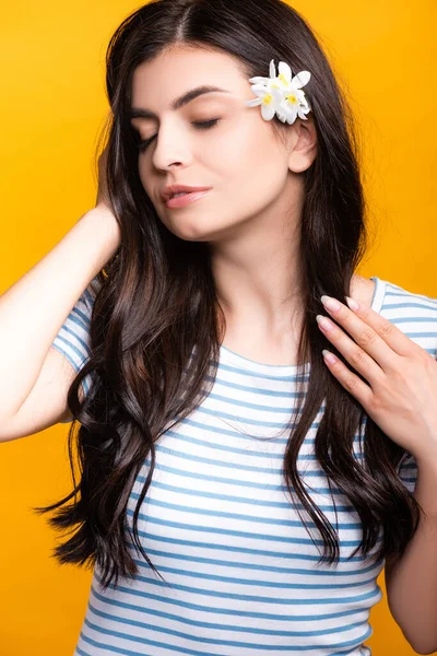 Brünette junge Frau mit Blumen im Haar und geschlossenen Augen isoliert auf gelb — Stockfoto